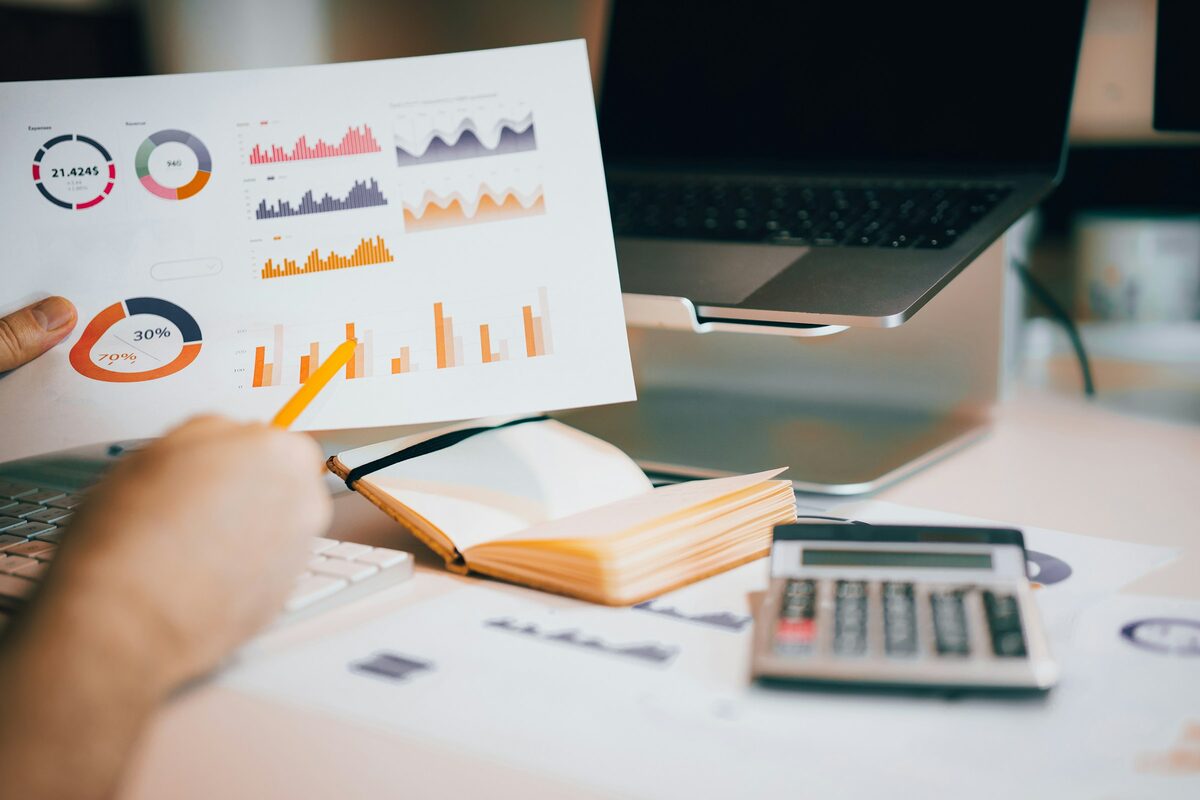 A printed chart held above a laptop on a desk